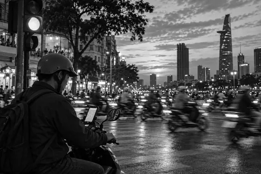Scooters crowd a Saigon street at dusk while a rider checks directions.